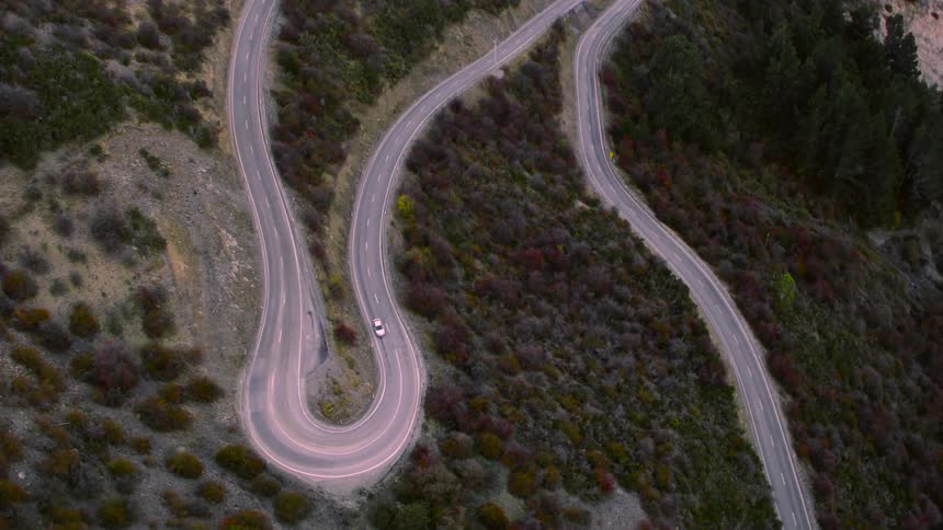 A white car is traveling on a winding road