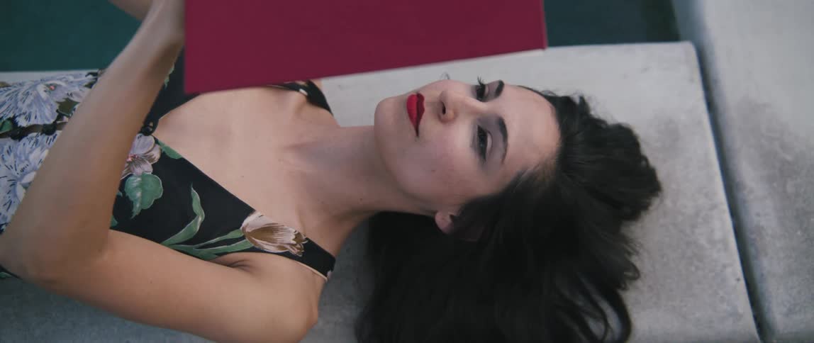 Young woman wearing a dress laying on the floor reading a book with red covers