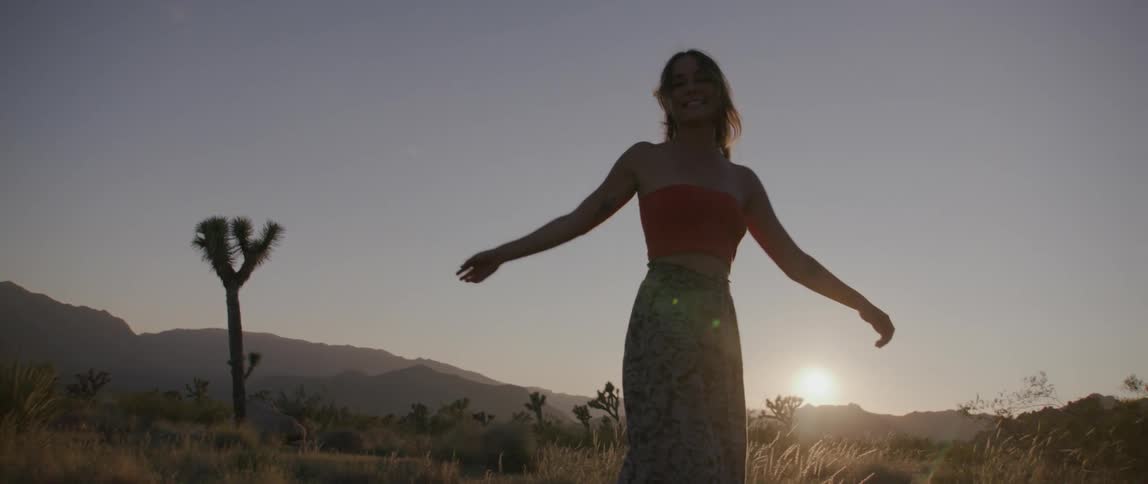 Silhouette of a young woman spinning on the desert at sunset