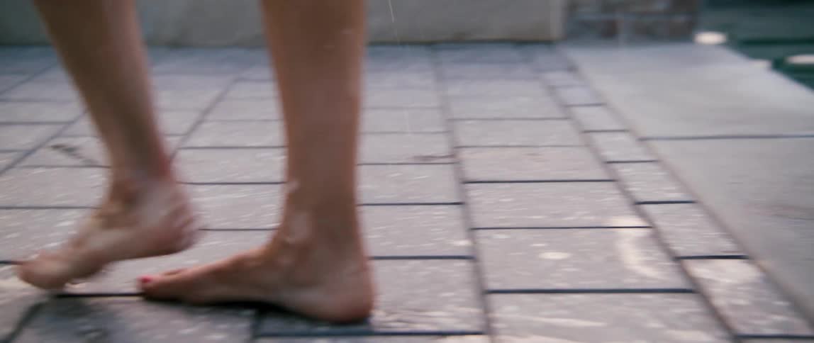 A woman steps out of a pool and walks through the grass