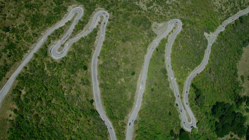 Aerial view of cars driving on roads in a rural area is displayed at midday