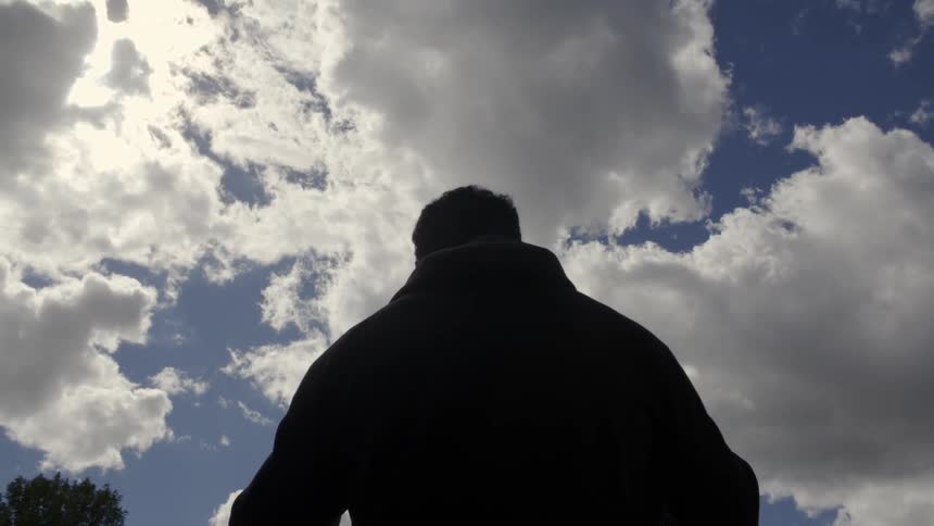 A man pulls off his hood on a cloudy day