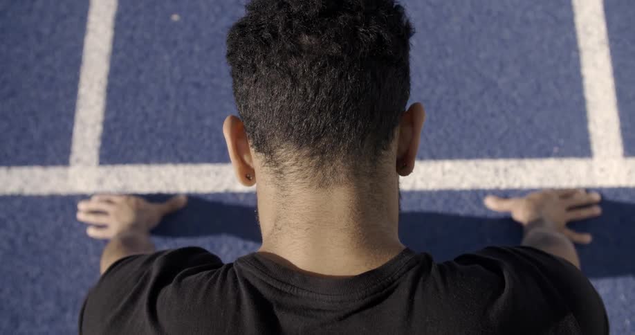 A person stretches on a blue track