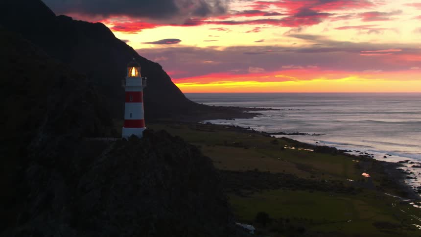 Light flashes in a lighthouse on a hill near the beach at sunset
