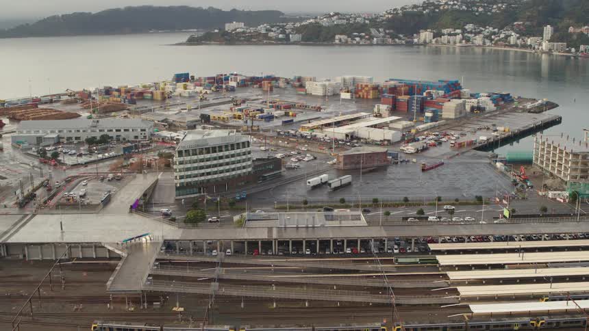A train station and a shipping yard next to a bay during the day