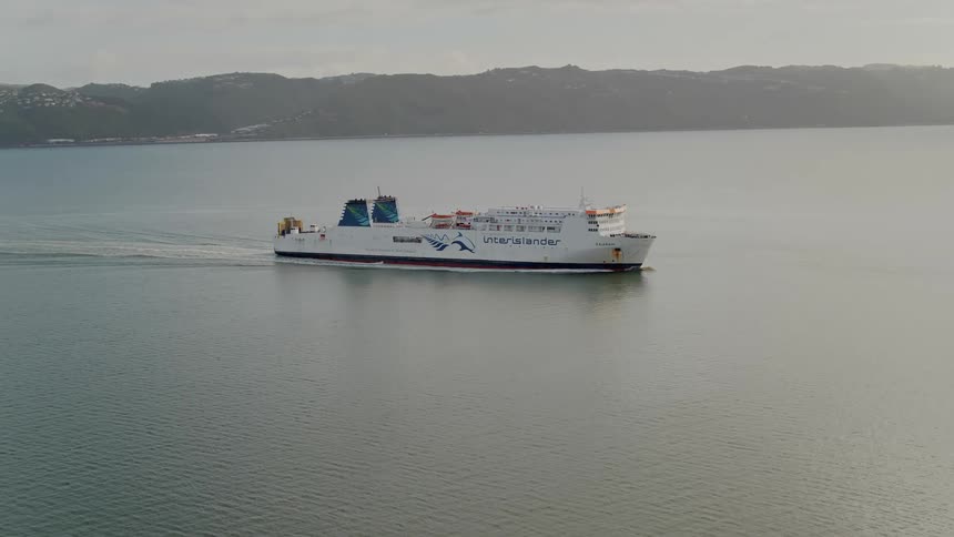 Aerial view of a ferry over the calm ocean water near the mounains at morning