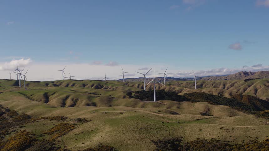 A landscape with hills and wind turbines with the sky and clouds in the background