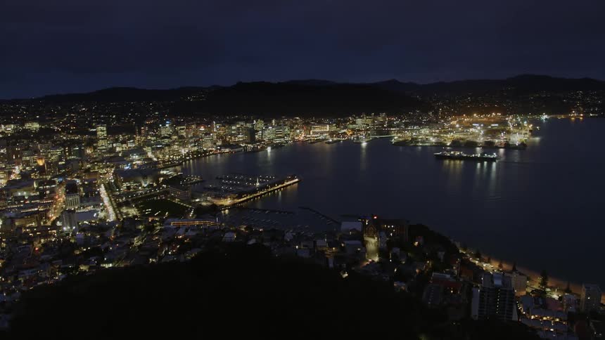 Lights illuminate the city as a boat in the lake heads to the dock