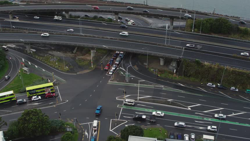 Cars and busses travel on the highway overpass next to the lake