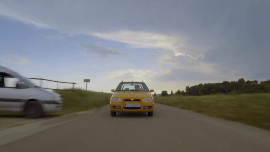 Car travels on a country road and passes a stopped van