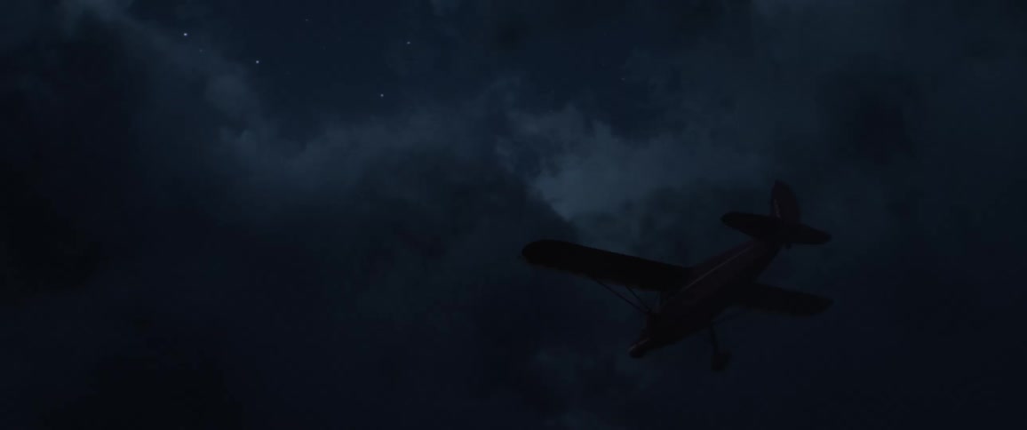 Aerial view of a small airplane with green and red light flying between the clouds at night