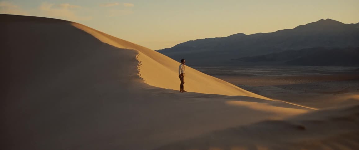 A man walking around out in sand dunes in the desert