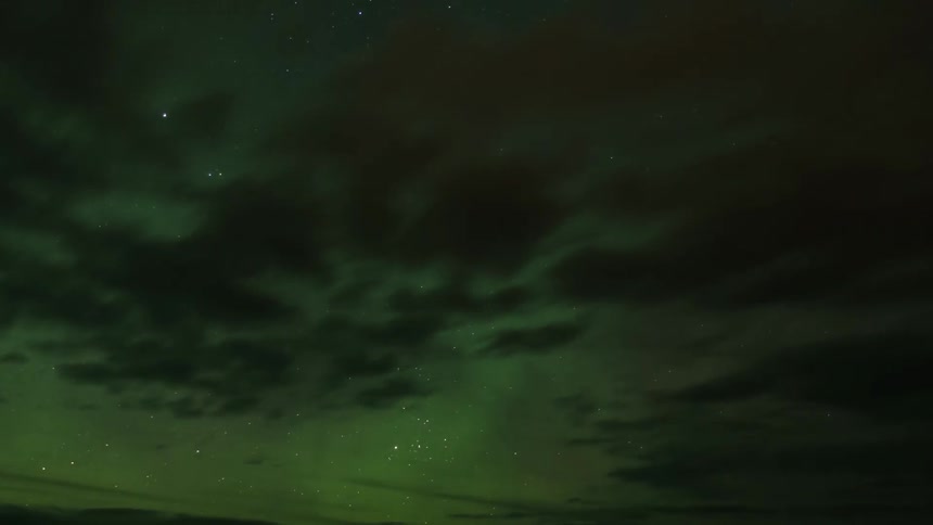 Time lapse of a star filled sky at night with aurora borealis and clouds