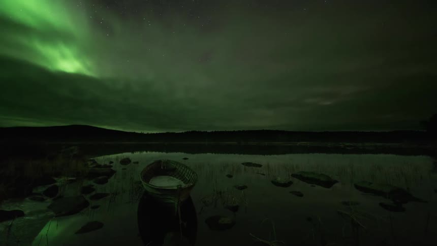 Clouds over a boat dissipate to reveal northern lights