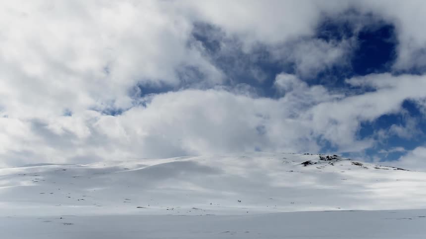 Timelapse of white clouds moving over a snow-covered landscape