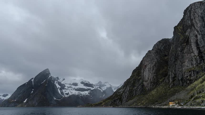 Clouds floating over a lake near snowy mountains