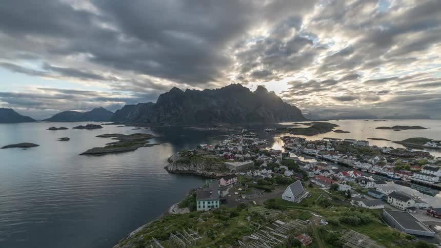Sun rising from behind mountains over a quaint fishing town