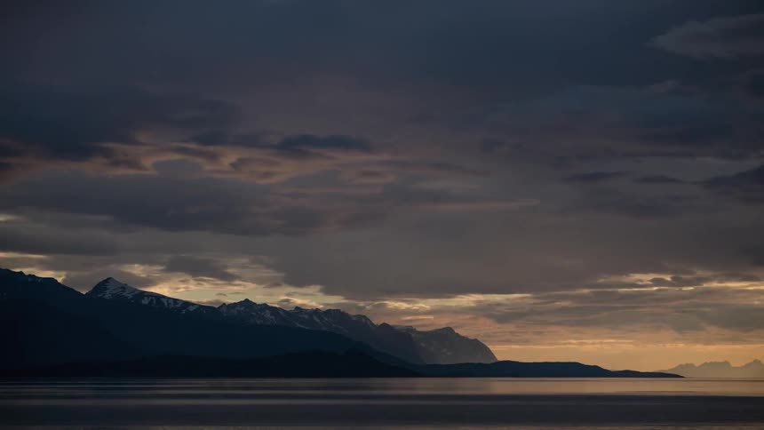 Colorful sunset and rolling clouds over mountains by the ocean
