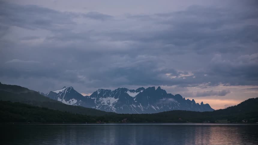 Clouds and mists form and move over mountains and a body of water