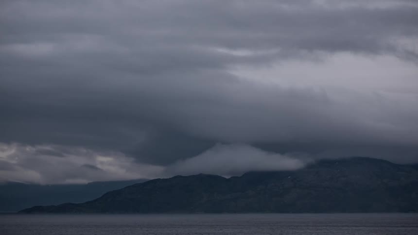 Time-lapse of storm clouds hovering over mountains and a lake