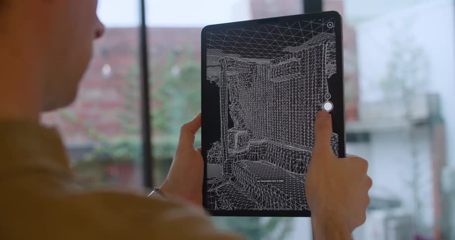 Man holds a tablet showing living room furniture and taps the screen to convert the photo to a black and white graphic