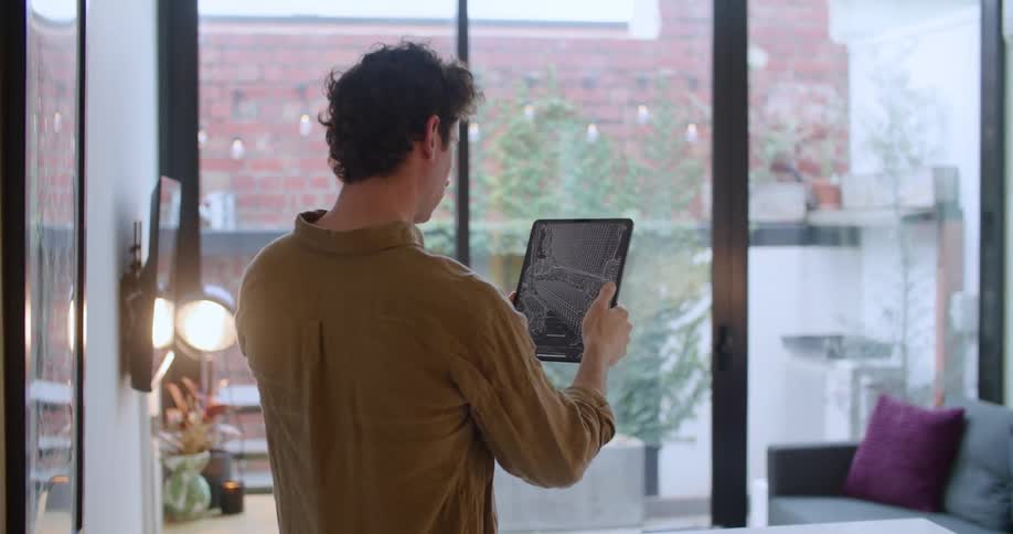 Man holds up a tablet as he views his sofa on the screen then taps a button to convert the screen to a black and white image