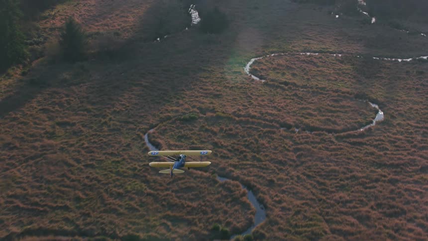 An aerial view of a plane flying over a field