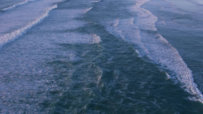 Ocean waves wash into a beach during the day