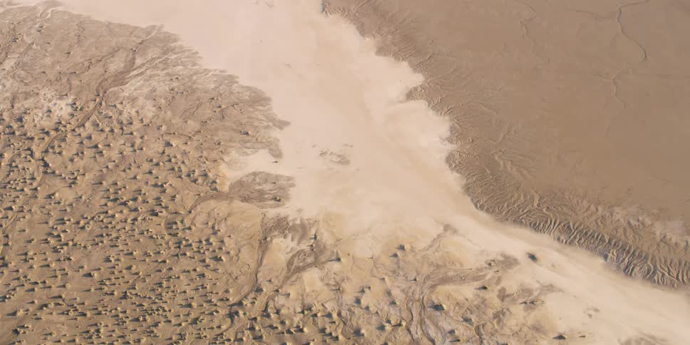 A muddy creek runs through a beach