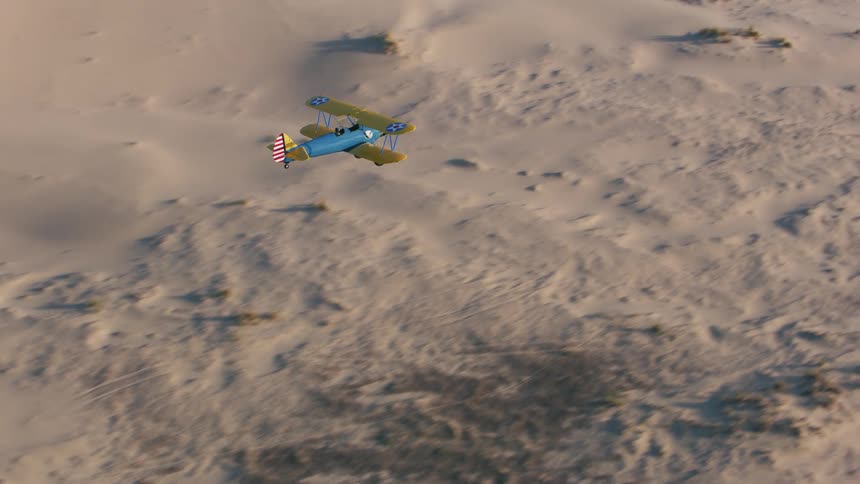 A person flies a biplane over a desert before crossing a river to reach a forest