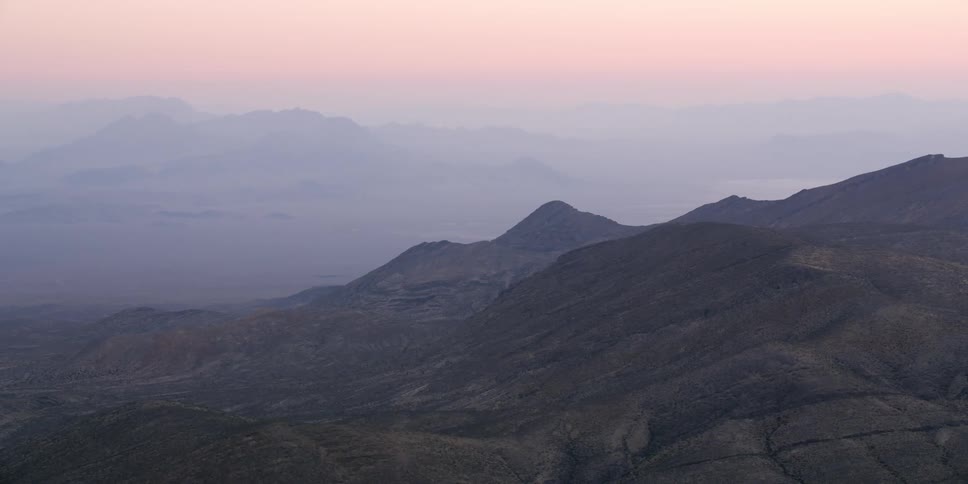 Thick fog obscures the sun setting over a canyon