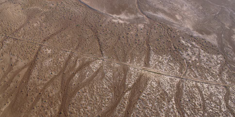 A long road crosses over an arid and dry desert landscape