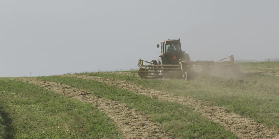 A tractor is working the fields on a very foggy day