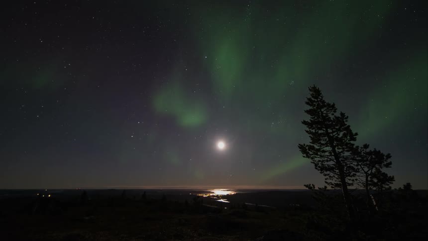 The moon and green aurora borealis in a night sky