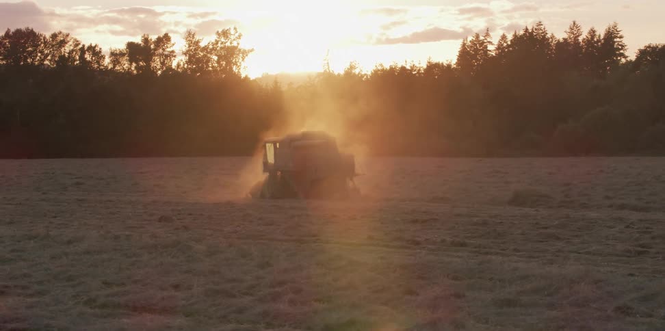Aerial view of a harvester working on a field at sunset