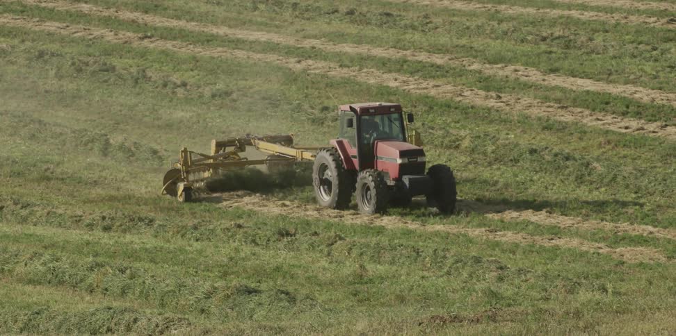 A tractor is working the fields on a sunny day