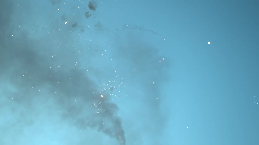 Fireworks exploding with smoke in the sky with clouds above