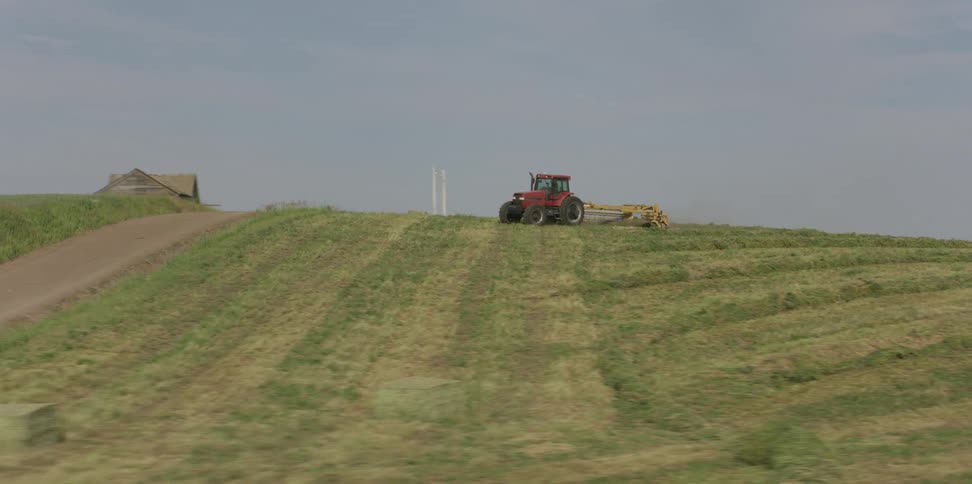A tractor is working the fields on a cloudy day