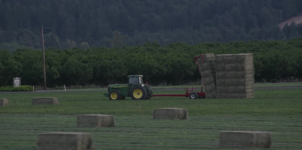 A tractor is stacking hay on the farm