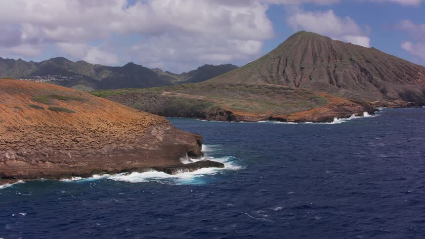 Aerial view of the blue ocean water crashing on the mountainous coastline