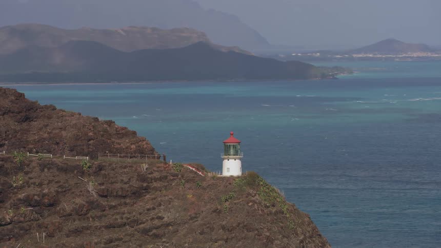 A lighthouse by a cliff with the ocean sky and clouds in the background