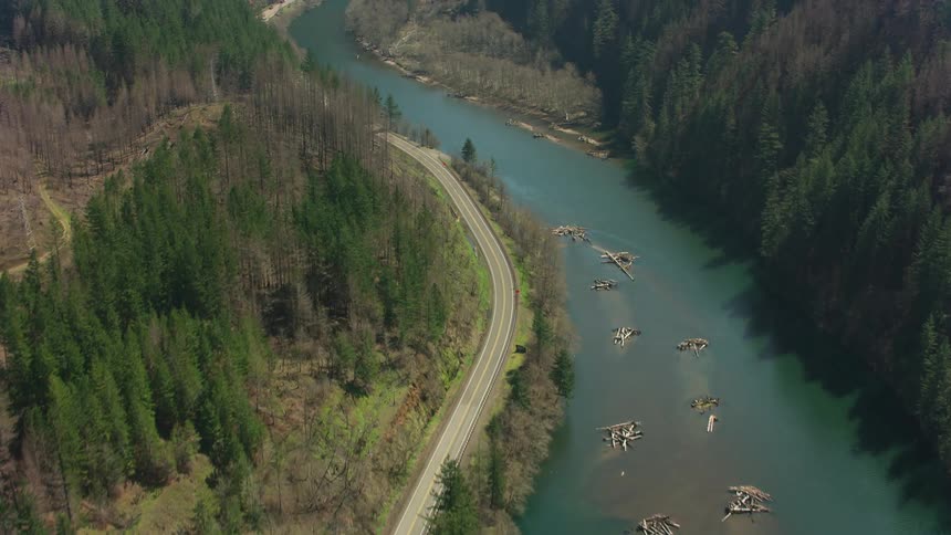 Aerial view of a road near a river between two mountains