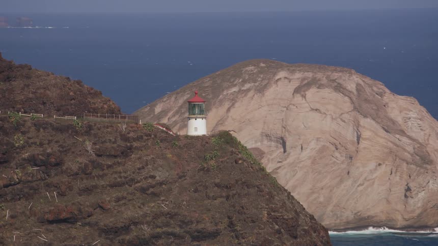 A lighthouse on a cliff with the ocean sky and clouds in the background