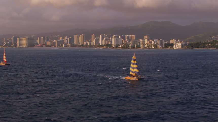 Sailboats travel along the water in the city
