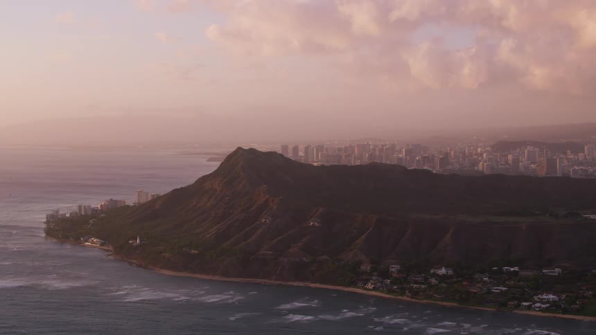 Aerial view of a coastal city near the mountains at sunset