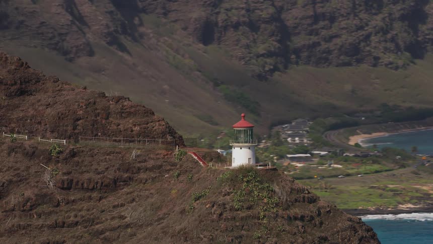 Aerial view of a lighthouse on a mountain near the ocean close to a small town