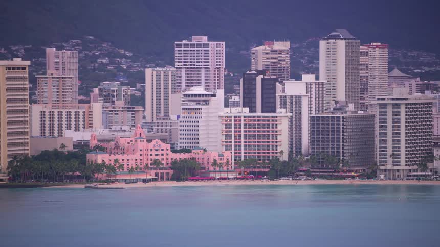 A large city with numerous towering buildings is situated along a beach lined coast