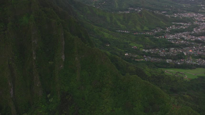 Buildings in a village sit at the base of the mountains with a forest nearby