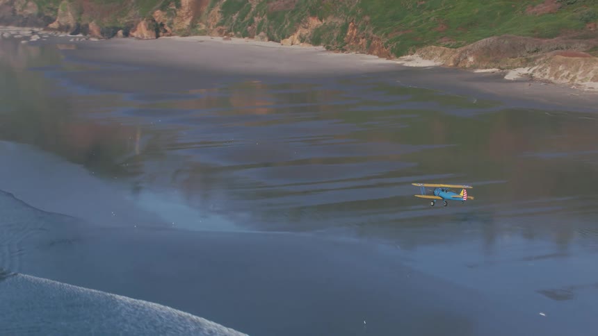 An aerial view of a plane flying over a beach