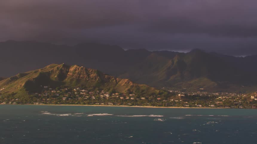 Dark clouds loom above a scenic coastline that has many dwellings on it